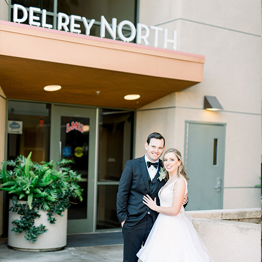 Couple in wedding dress and suit in front of Del Ray North
